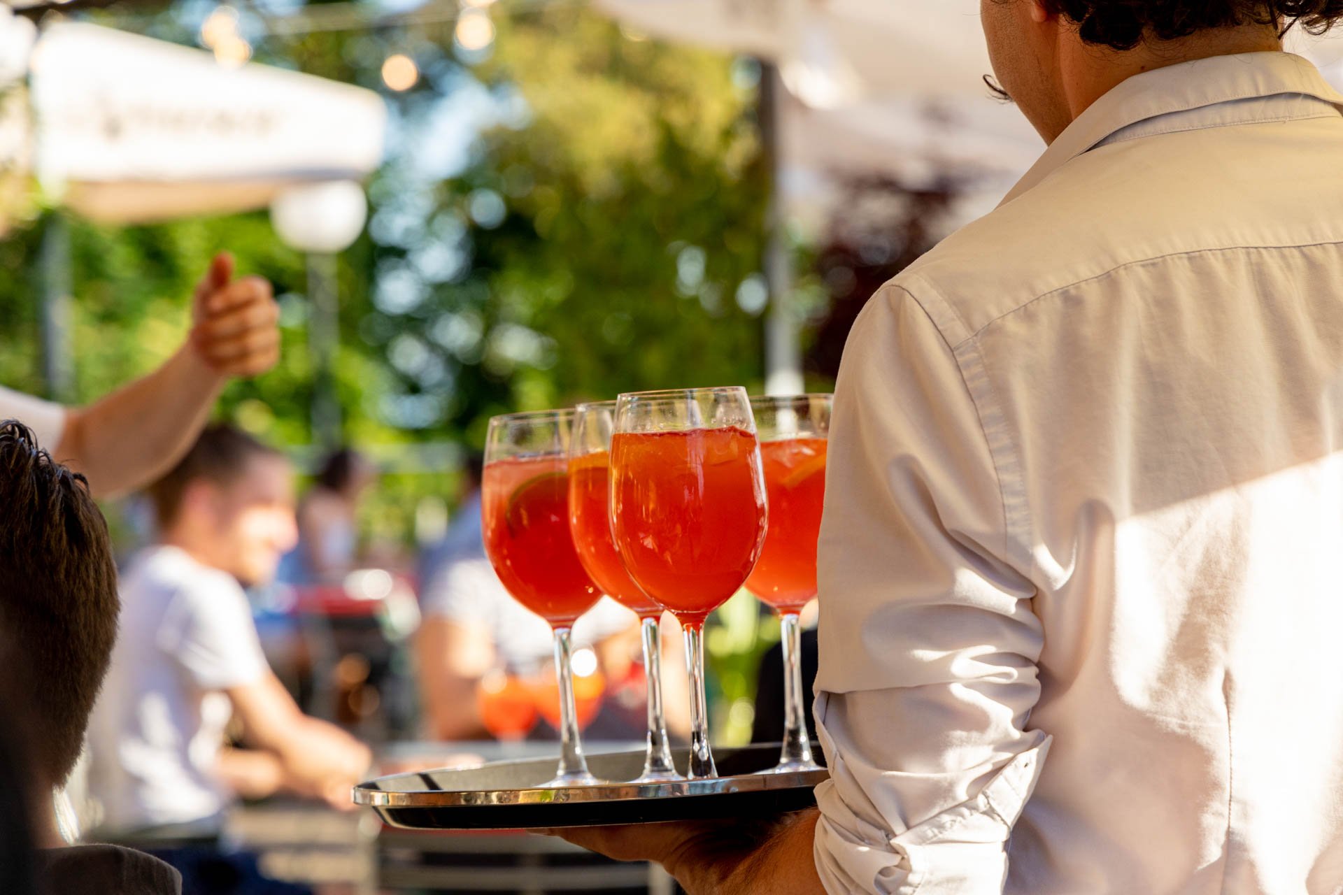 Mitarbeiter serviert ein Tablar voller Spritz